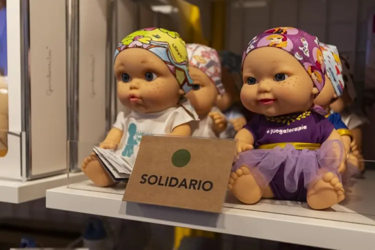Un expositor de muñecas de colores vestidas con diversos trajes, con un cartel que pone «SOLIDARIO» bien visible delante.