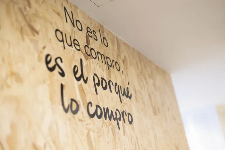 Una pared de madera exhibe la frase " No es lo que compro, es el porqué lo compro".