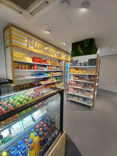 Un minimercado bien iluminado con estanterías coloridas. Se exhiben refrigerios, bebidas, artículos para el hogar y textiles, creando un ambiente acogedor.