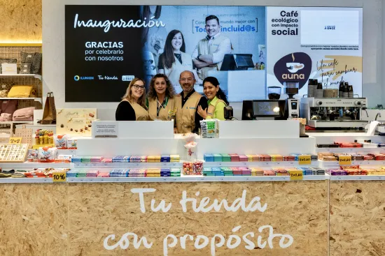 Tu Tienda en Hospital Rey Juan Carlos de Móstoles recién inaugurada exhibe varios productos y una máquina de café en el mostrador, donde nos encontramos con 4 empleados sonriendo. 