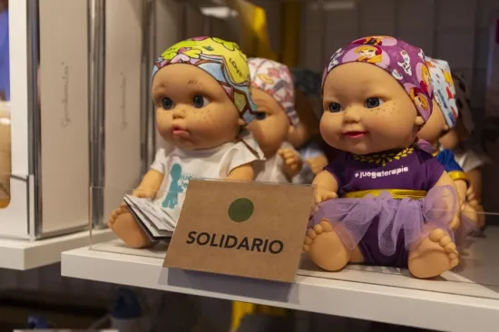 Un expositor de muñecas de colores vestidas con diversos trajes, con un cartel que pone «SOLIDARIO» bien visible delante.