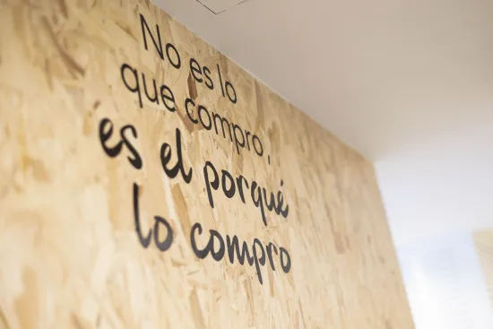 Una pared de madera exhibe la frase " No es lo que compro, es el porqué lo compro".