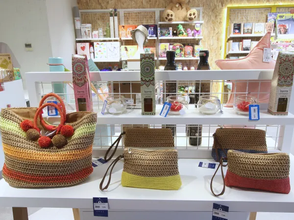 Un expositor de bolsos con múltiples colores y otros productos visibles de fondo.