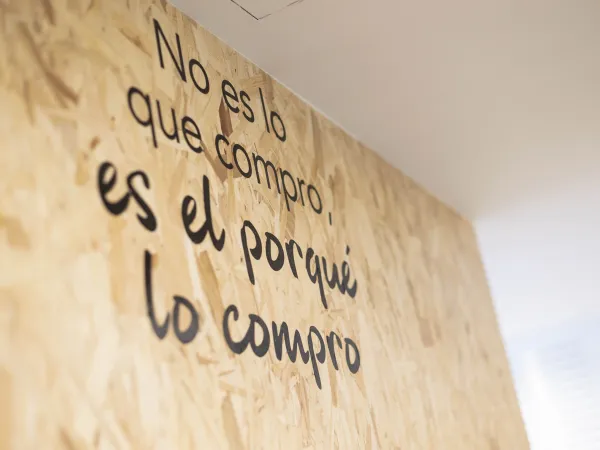 Una pared de madera exhibe la frase " No es lo que compro, es el porqué lo compro".